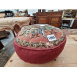 A RED CUSHION OR FOOTREST WITH A FLORAL BEAD WORK TOP
