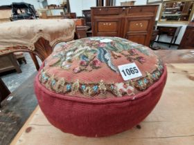 A RED CUSHION OR FOOTREST WITH A FLORAL BEAD WORK TOP