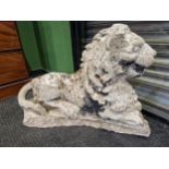 AN ANTIQUE RECONSTITUTED STONE FIGURE OF A RECUMBENT LION.