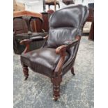 A VICTORIAN MAHOGANY ARMCHAIR UPHOLSTERED IN BROWN, THE BOBBIN TURNED FRONT LEGS ON CASTER FEET