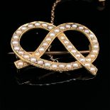 AN ANTIQUE GOLD AND SEED PEARL SWEETHEART LOVERS KNOT, ALSO KNOWN AS A STAFFORD KNOT BROOCH. THE