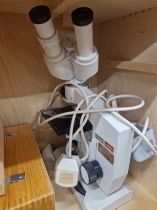 A CASED LOMO BINOCULAR MICROSCOPE WITH AN ELECTRIC LIGHT SOURCE AND SOME ACCESSORIES AND