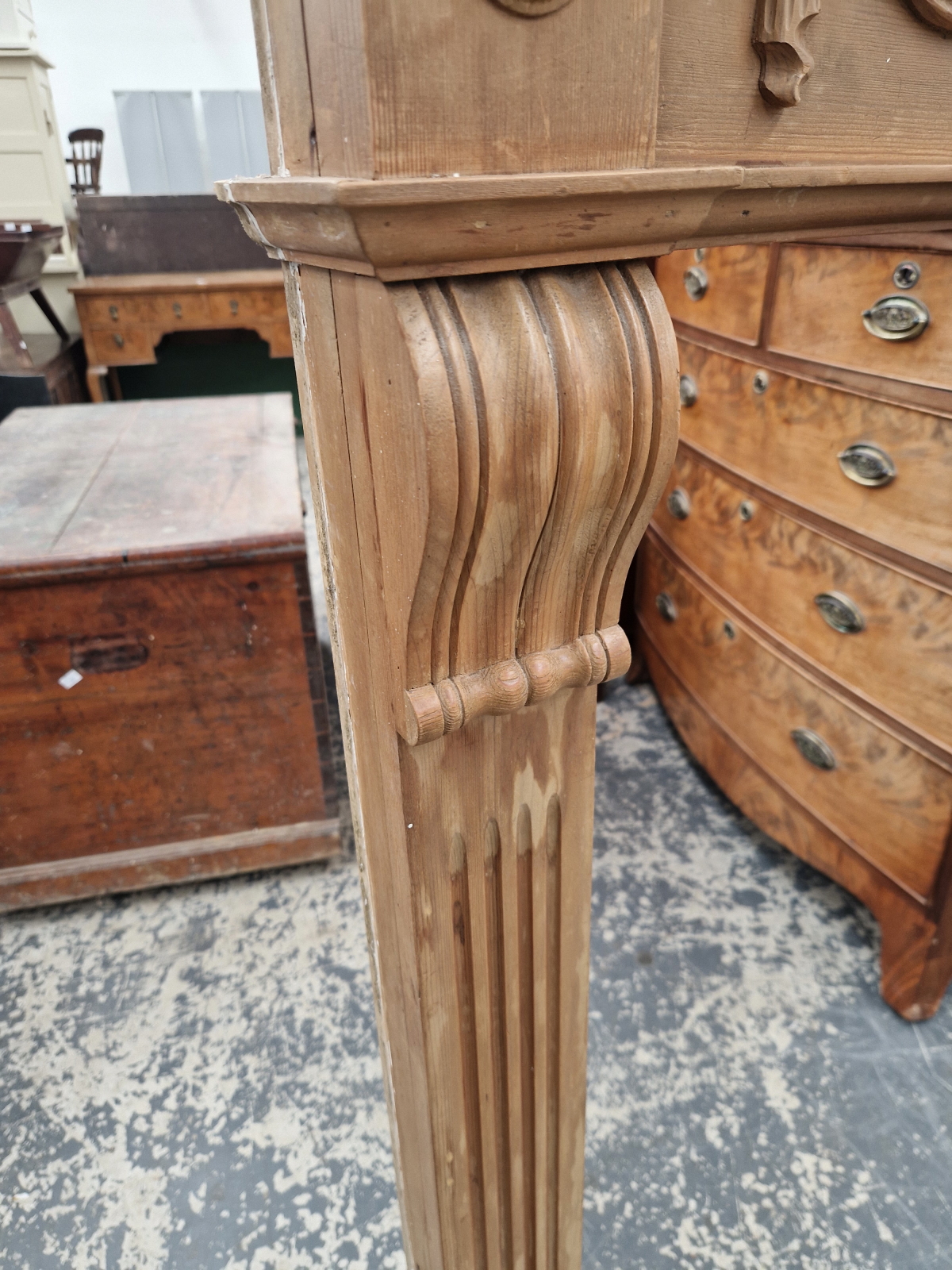 A REGENCY STYLE PINED FIRE SURROUND, THE FLUTED PILASTER SIDES CRESTED BY A CENTRAL URN FLANKED BY - Image 5 of 6