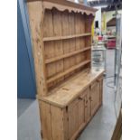 A RUSTIC PINE DRESSER WITH INTEGRAL SEMI HOODED PLATE RACK.