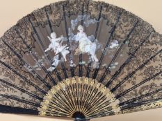 A BOXED BLACK LACE FAN, THE LEAF PAINTED WITH TWO AMORINI PLAYING TO A SEATED LADY, THE GUARD STICKS