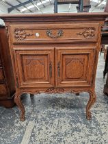 AN OAK SIDE CABINET WITH A DRAWER ABOVE PANELLED DOORS, CABRIOLE FRONT LEGS ON CARVED FEET