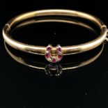 AN ANTIQUE BANGLE SET WITH A RUBY AND DIAMOND HORSESHOE. THE HINGED BANGLE UNHALLMARKED, ASSESSED AS