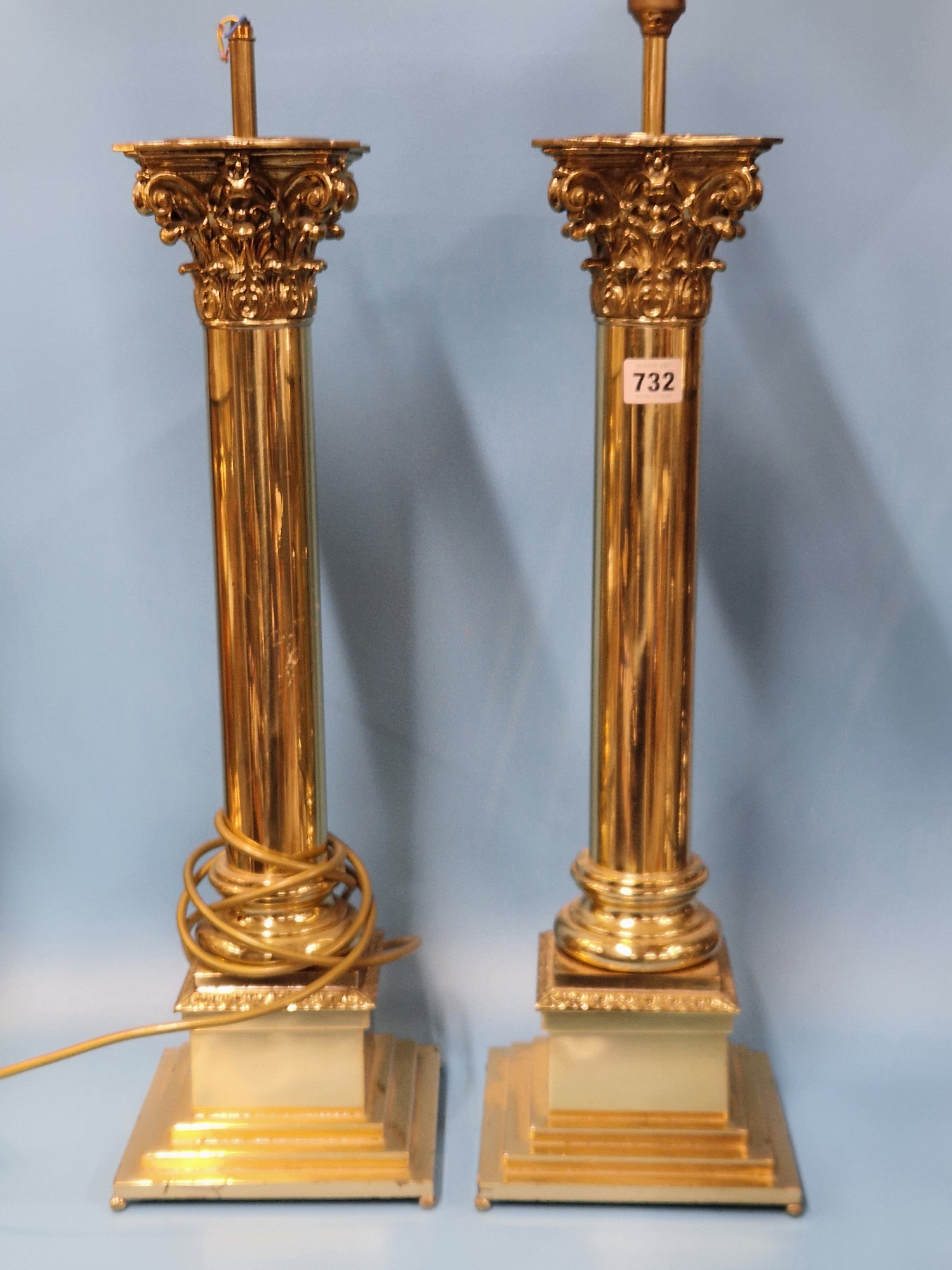 A PAIR OF BRASS COLUMN LAMPS WITH CORINTHIAN CAPITALS AND STEPPED SQUARE FEET. H 66cms.