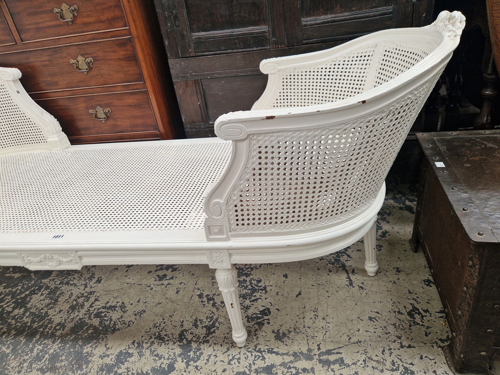 A WHITE PAINTED CANED CHAISE LONGUE, THE ROUNDED ENDS CRESTED BY CARVED FLOWERS, THE FLUTED - Image 2 of 5