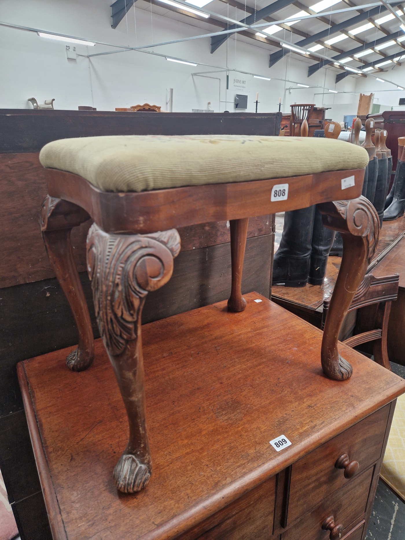 A MAHOGANY STOOL WITH A DROP IN FLORAL NEEDLE WORK SEAT, THE CABRIOLE LEGS CARVED WITH FOLIAGE AT