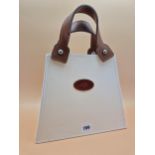 A TABLE LAMP MODELLED AS A CREAM COLOURED HANDBAG WITH BROWN LEATHER HANDLES. H 37cms.