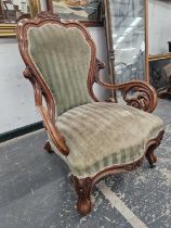 A VICTORIAN WALNUT SHOW FRAME ARMCHAIR CRESTED BY A PAIR OF CARVED FLOWER HEADS THE ARMS SUPPORTED