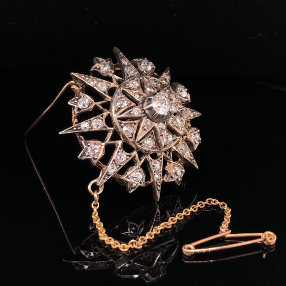 AN ANTIQUE OLD CUT DIAMOND RADIATING STAR BROOCH WITH ATTACHED SAFETY CHAIN. THE PRINCIPLE OLD CUT