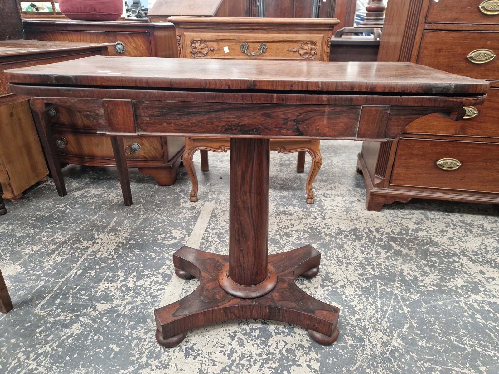 A 19th C. ROSEWOOD SWIVEL TOP GAMES TABLE ON A GUN BARREL COLUMN, QUADRIPARTITE PLINTH AND FOUR