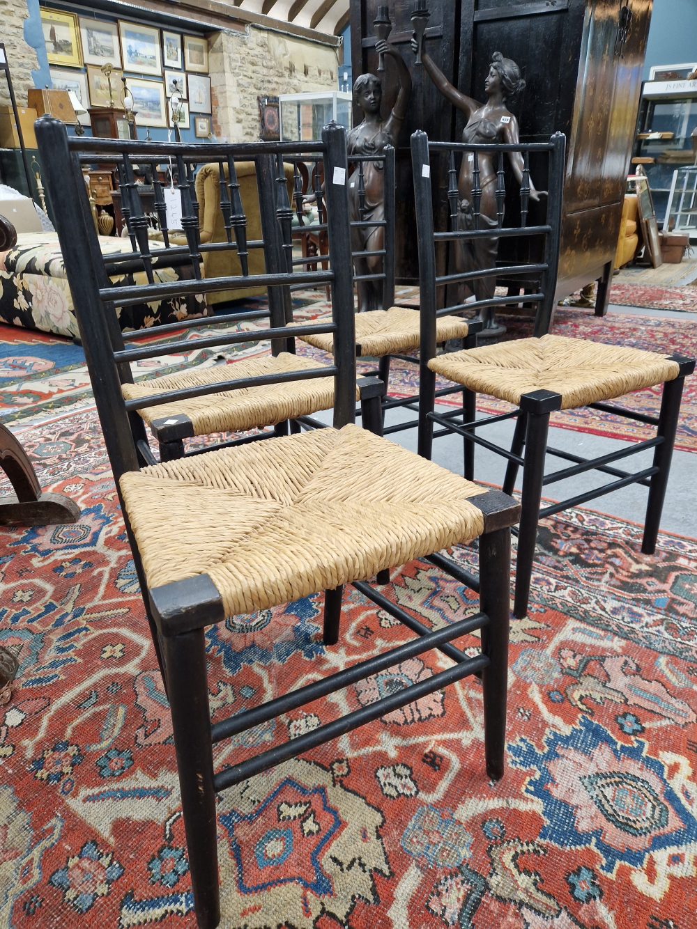 A SET OF FOUR WILLIAM MORRIS EBONISED CHAIRS WITH RUSH SEATS