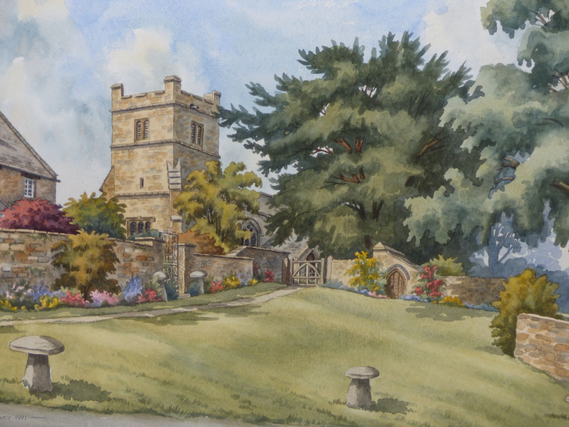 SUSAN WOOLLEY (20TH CENTURY), GARDEN WITH CHURCH AND COTTAGE BEYOND, SIGNED AND DATED 1991,