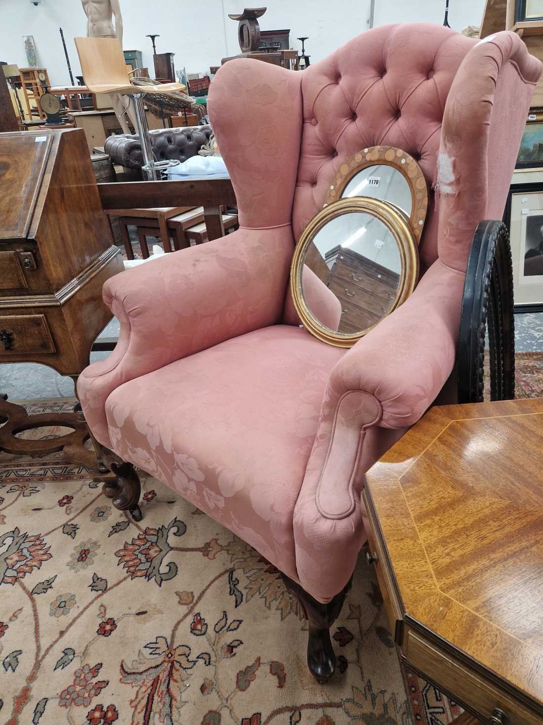 An antique wing back arm chair on carved cabriole legs.