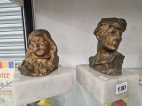A bronze head of a girl and of a boy, both mounted on white marble blocks and indistinctly signed