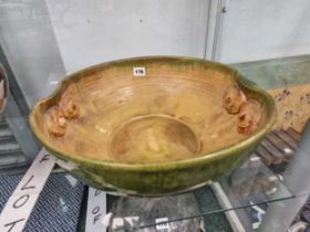 A Bretby type green and yellow glazed bowl with owl mask handles This has t6wo rim chips and has