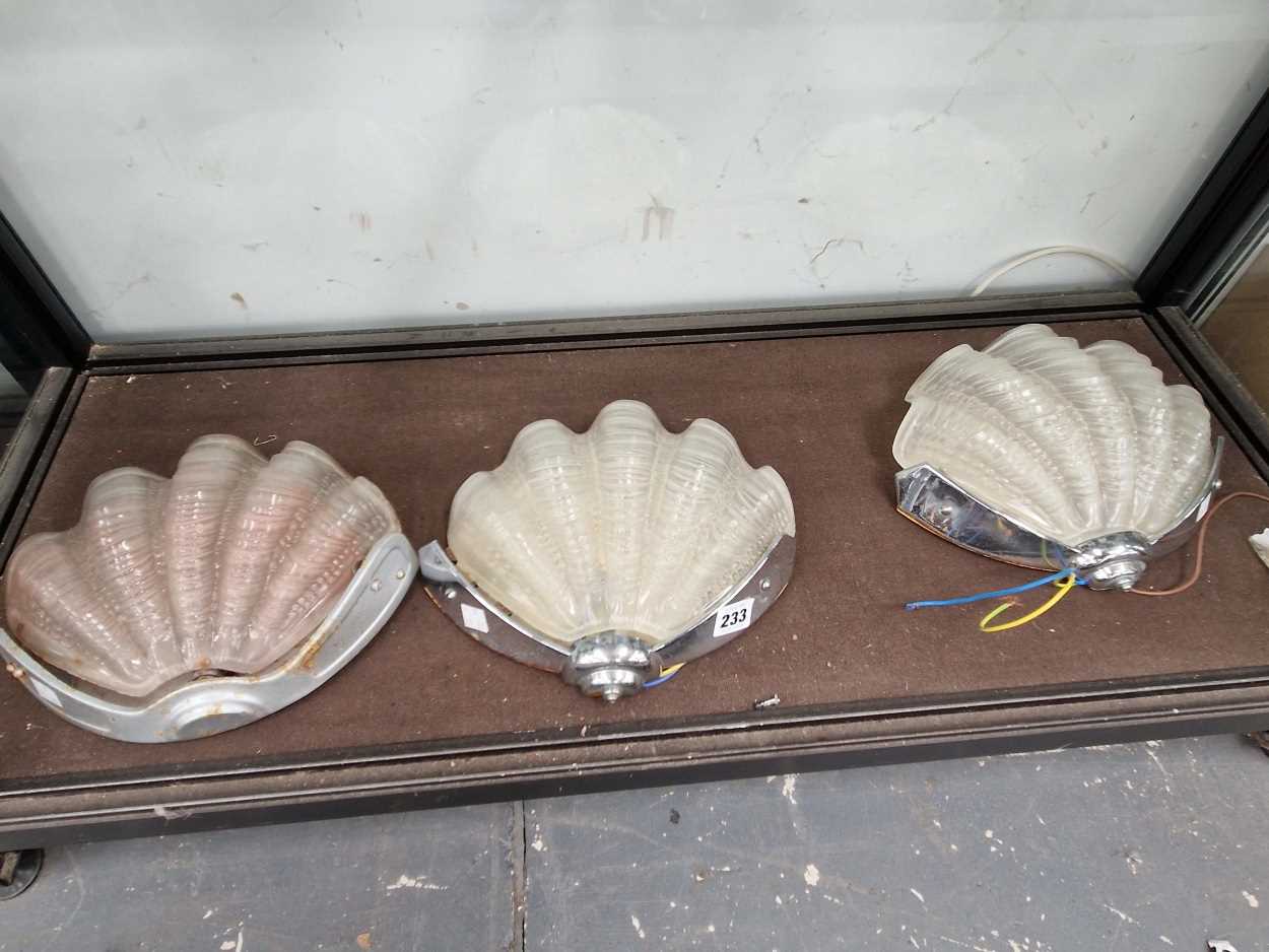 A set of three chrome wall lights with frosted glass shell shades