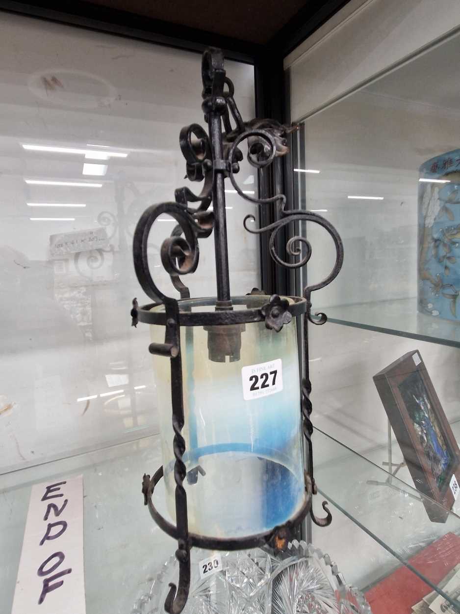 A wrought iron lantern containing a cylindrical vaseline glass shade