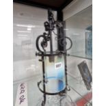 A wrought iron lantern containing a cylindrical vaseline glass shade