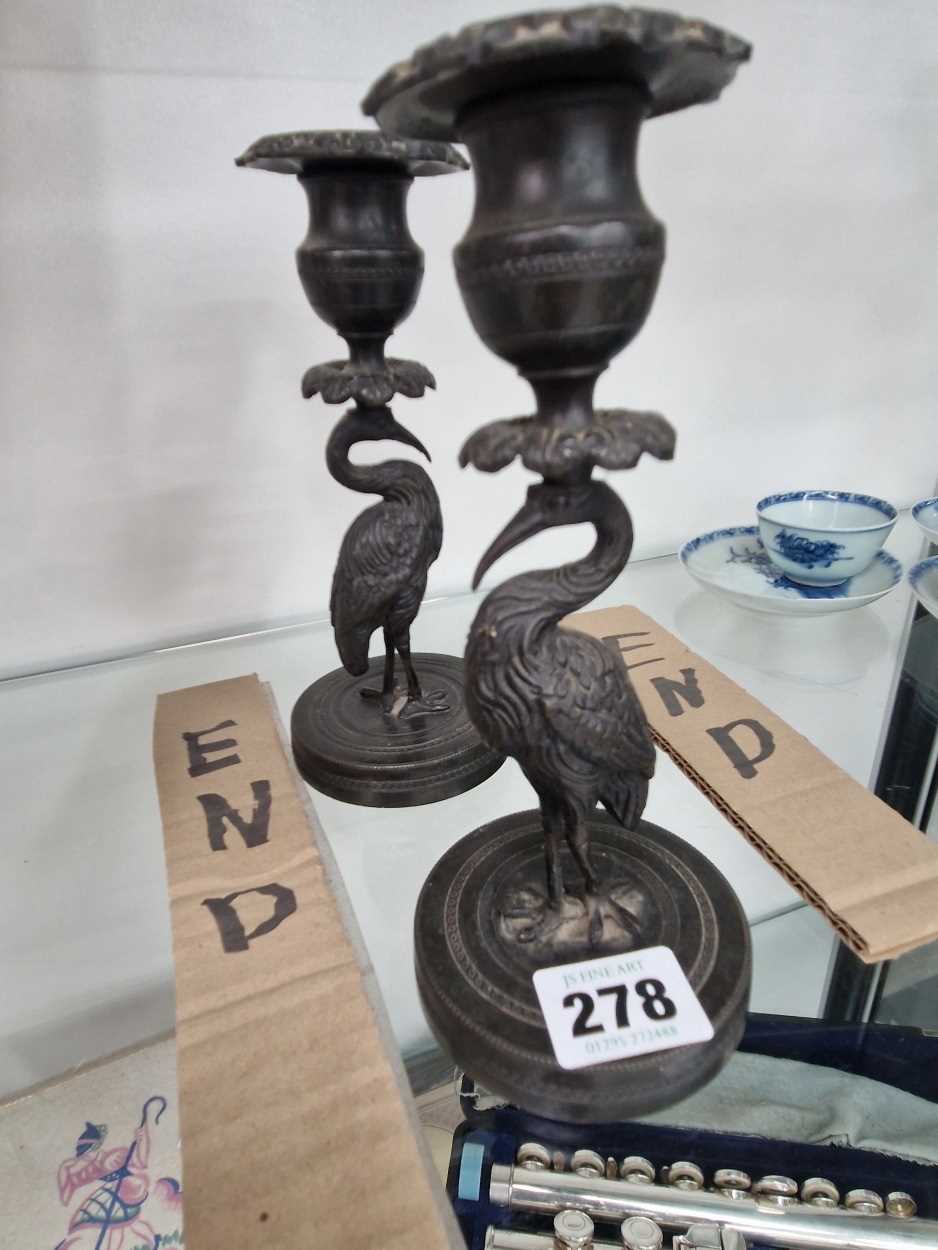 A pair of bronze candlesticks, the nozzles supported on the heads of storks