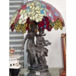 A pair of bronzed classical ladies as a table lamp with a leaded glass shade