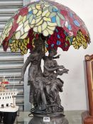 A pair of bronzed classical ladies as a table lamp with a leaded glass shade