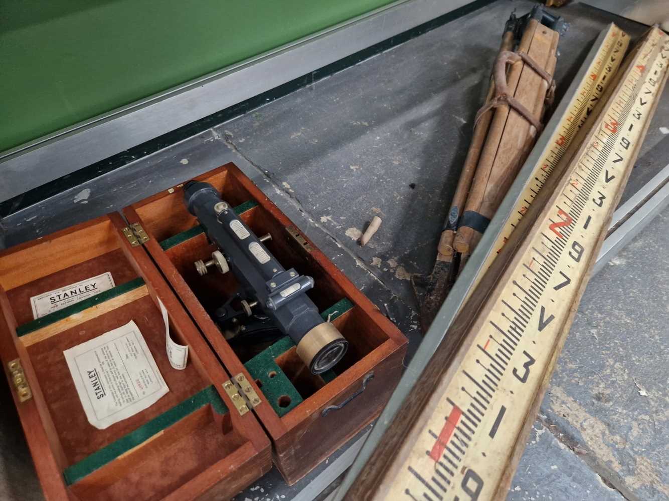 A vintage Stanley surveying level with tripod and pools in wooden case.