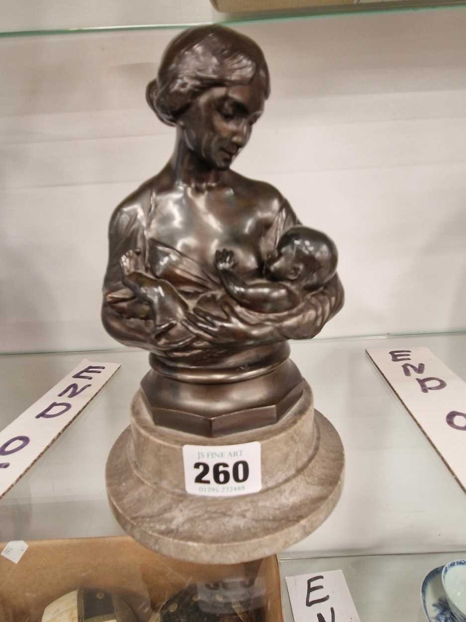 A bronzed bust of a mother feeding her baby