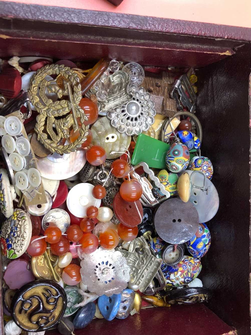 A collection of antique and later buttons, beads, military pins, etc contained in a red vintage - Bild 3 aus 3