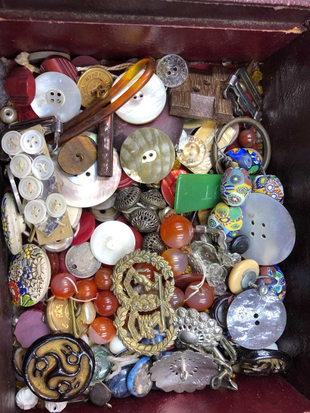 A collection of antique and later buttons, beads, military pins, etc contained in a red vintage - Bild 2 aus 3