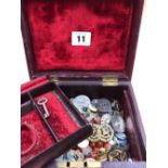A collection of antique and later buttons, beads, military pins, etc contained in a red vintage