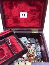 A collection of antique and later buttons, beads, military pins, etc contained in a red vintage