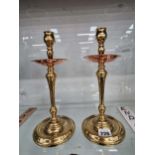 A pair of W.A.S. Benson brass candlesticks with copper drip pans