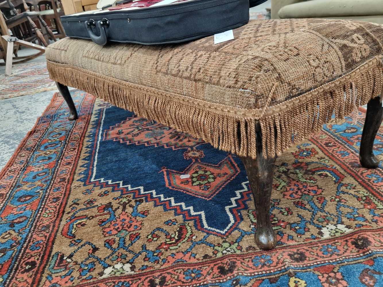 A vintage lonh footstool with carpet upholstery.