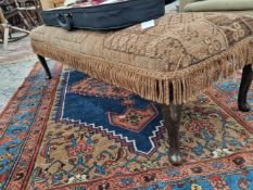 A vintage lonh footstool with carpet upholstery.