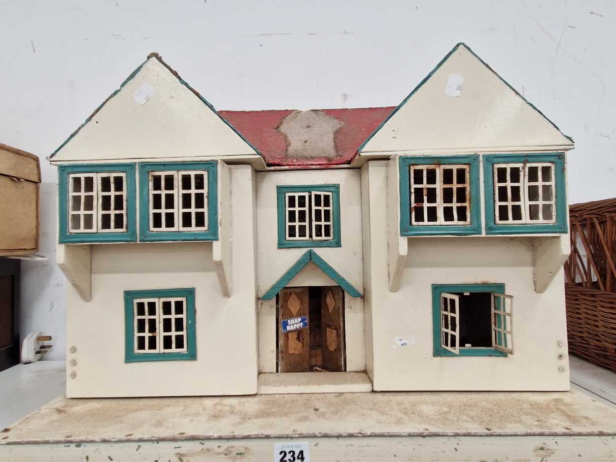 A white twin gabled dolls house with blue window frames