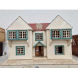 A white twin gabled dolls house with blue window frames