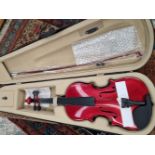 A full size violin with red lacquer body, in fitted case with bow.