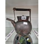 A Dresser design copper kettle. There is a dent to one side. The wooden handle is not aligned to a