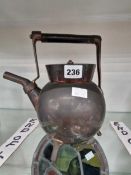 A Dresser design copper kettle. There is a dent to one side. The wooden handle is not aligned to a