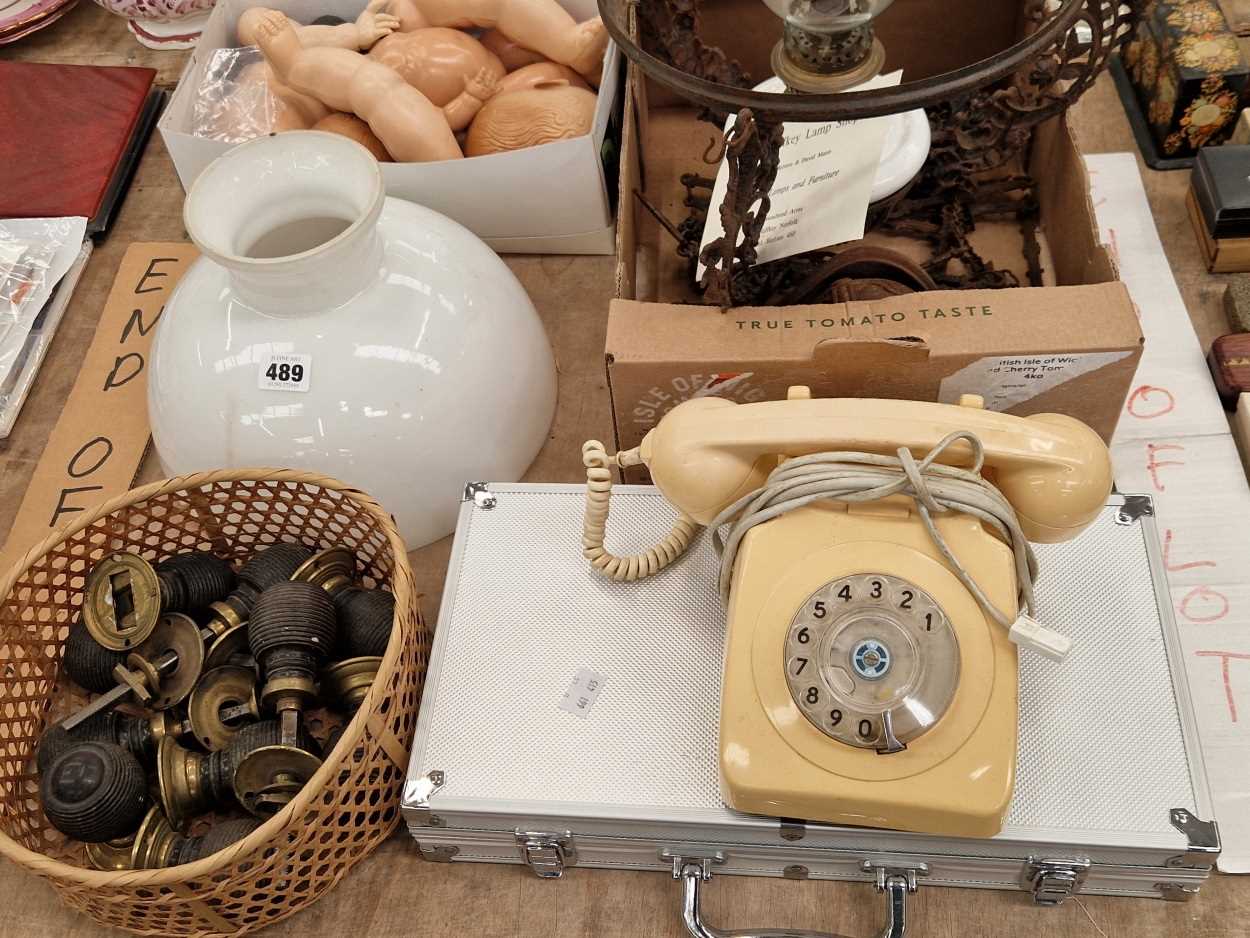 A ceiling oil lamp, ebony door knobs, a white telephone receiver, an aluminium case of gaming