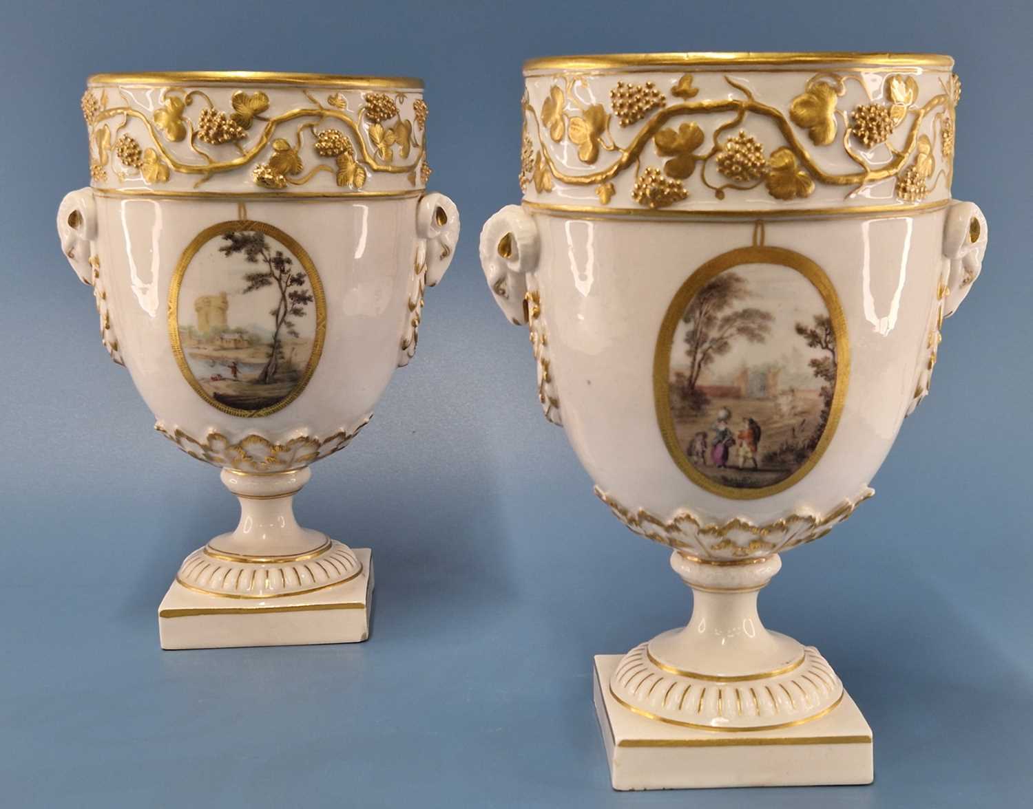 A pair of Derby ram handled vases supported on square feet painted with landscapes by Askew or
