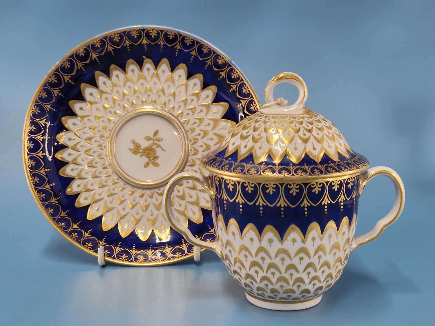 A Derby two handled cup, cover and saucer with royal blue rims enclosing gilt and moulded