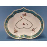 A Derby kidney shaped dish painted with a turquoise rim band gilt with grapes and enclosing four