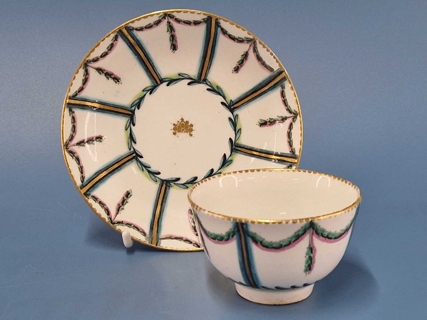 A Chelsea Derby tea bowl and saucer painted in pink, turquoise and green with drapery swags in