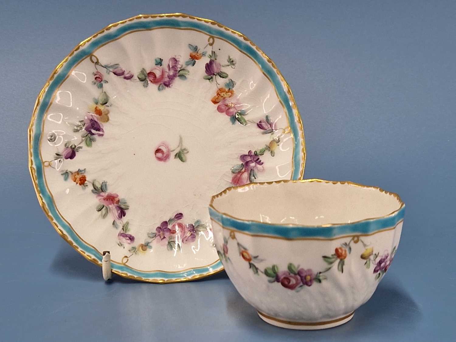 A Derby wrythen tea bowl and saucer painted with a turquoise blue band and floral swags, blue marks,