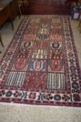 A Middle Eastern wool floor rug with central segmented panel of floral and geometric motiffs, 300